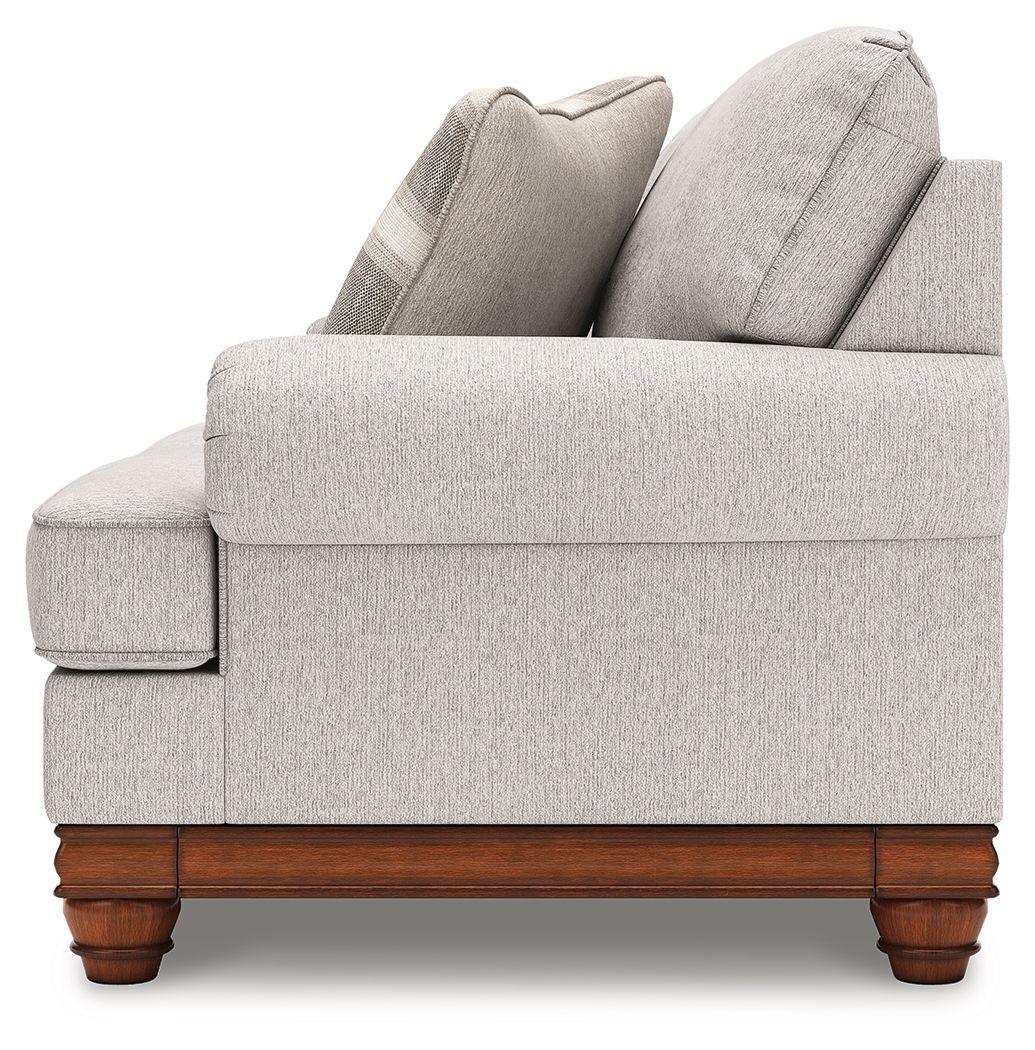 Upholstered loveseat side view with solid back, rolled arms, and wooden feet