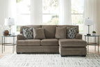 Taupe sofa chaise with two geometric patterned throw pillows in a living room setting