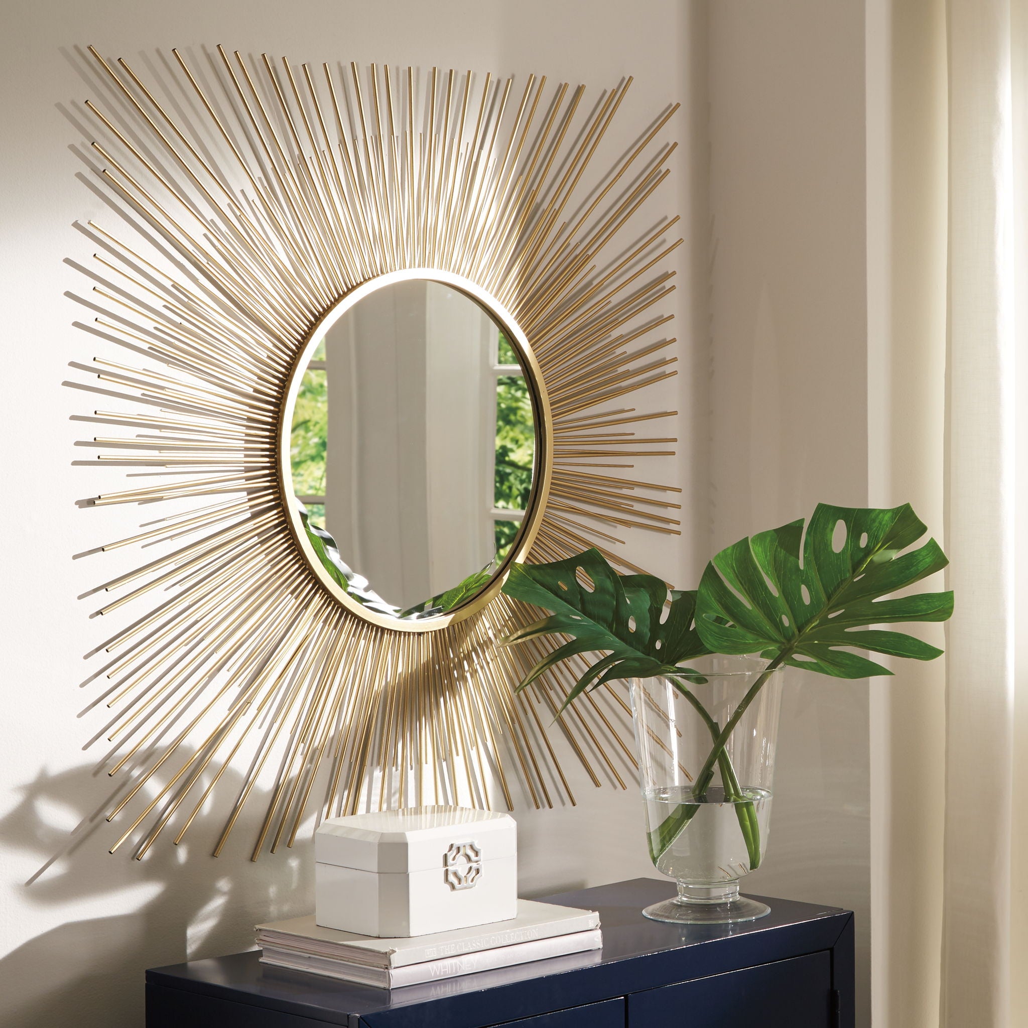 Gold round accent mirror with radiating rods and a reflective glass face