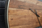 Close-up of brown wood-grain wall clock face with black hands and silver bezel