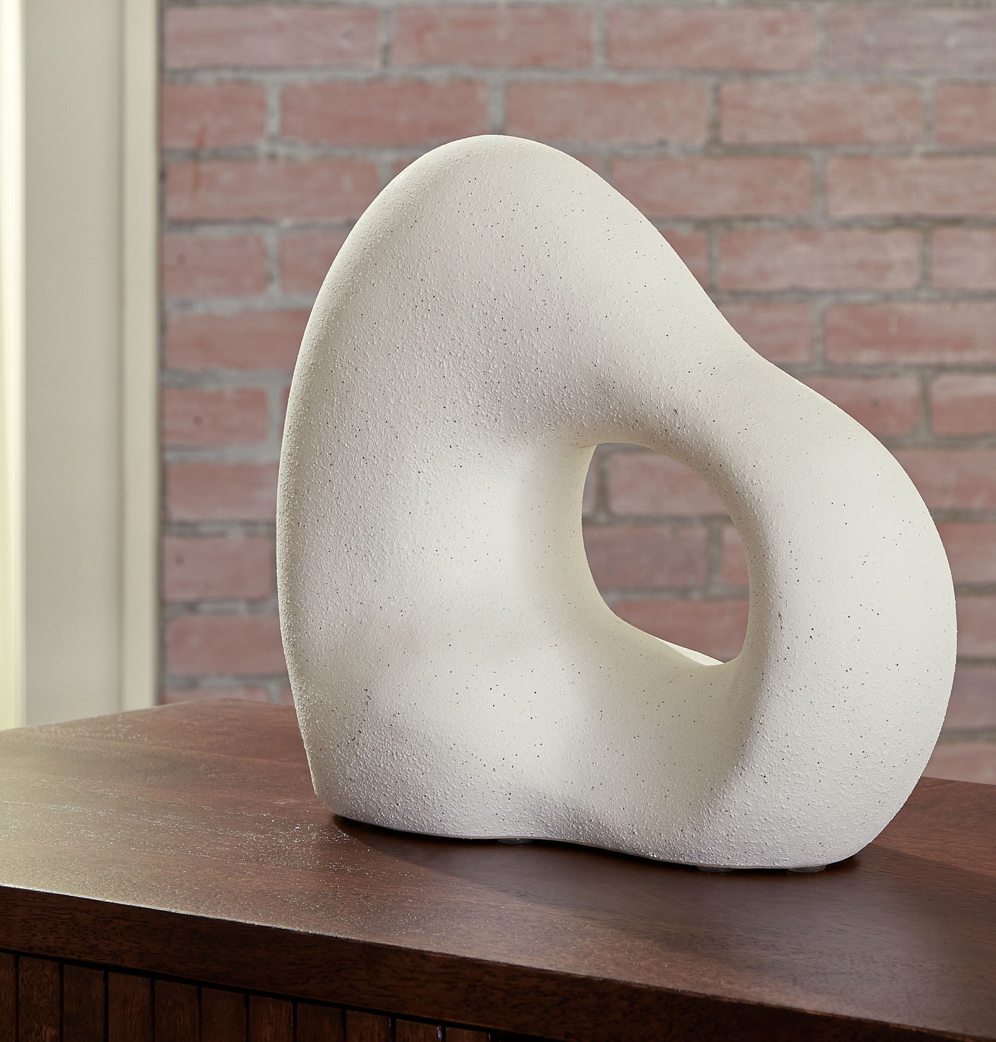 Off-white abstract sculpture with standing teardrop shape and oval hole