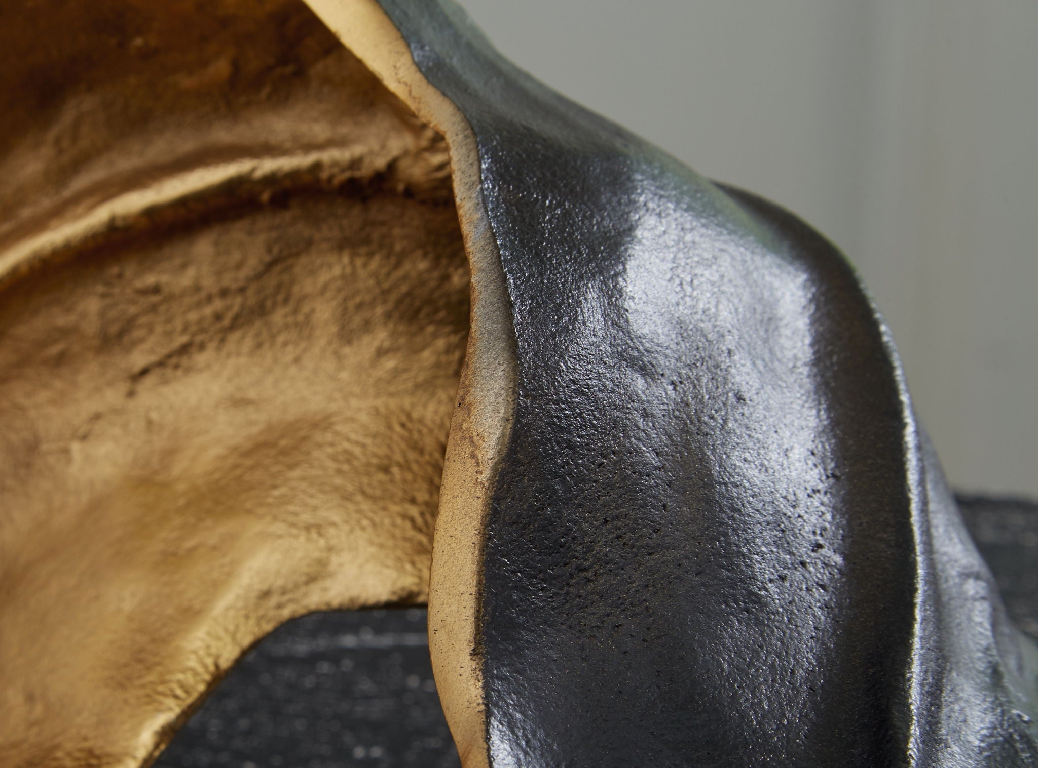 Close-up of metal sculpture with gold interior and dark black curved edge