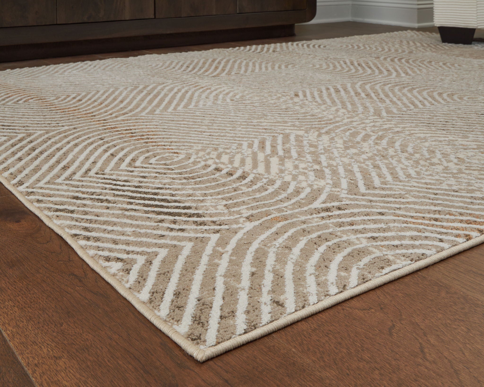 Beige rug corner with concentric diamond and chevron pattern, low pile