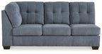 Blue-gray fabric sofa with tufted back panels, two wide seat cushions, and dark block legs