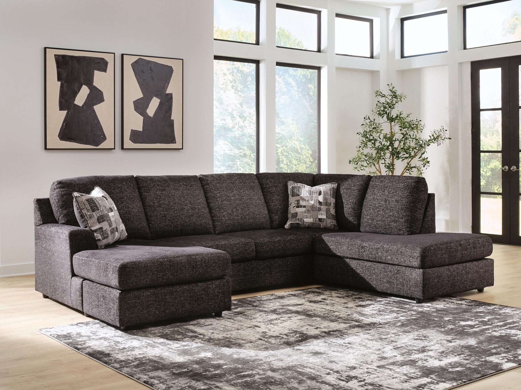 Dark charcoal fabric sectional sofa with chaise, tufted back cushions, and three patterned throws