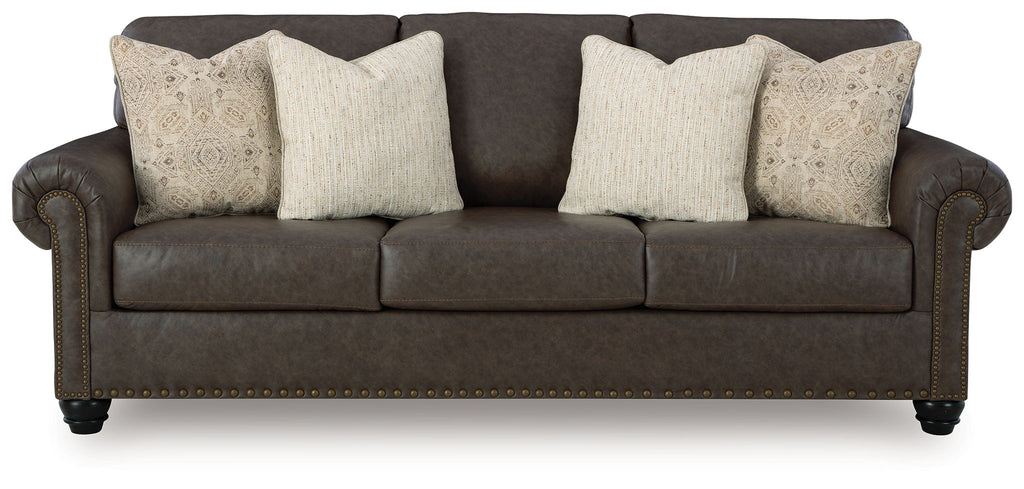 Dark brown upholstered sofa with three seats and two patterned accent pillows.