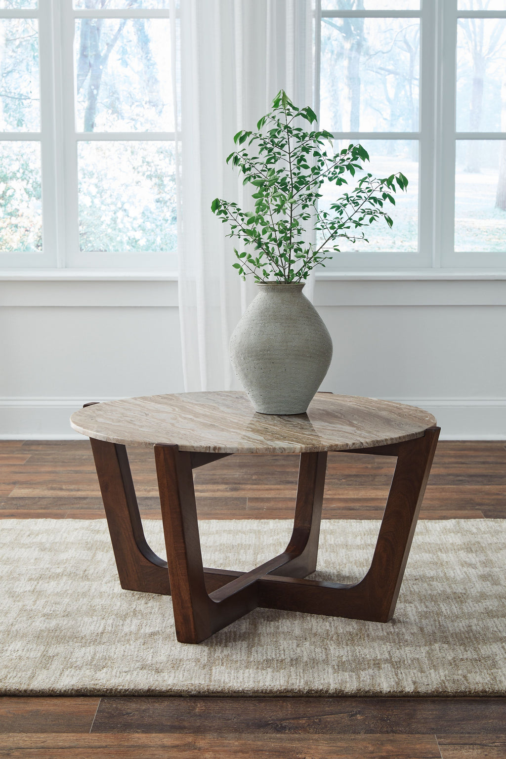 Round warm brown wooden cocktail table with curved supports and round top