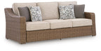 Beige fabric sofa with wicker base and two patterned throw cushions
