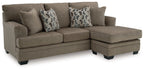 Taupe sofa chaise with two geometric patterned throw pillows and extended chaise section