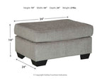 Gray upholstered ottoman with square top and black legs, front view