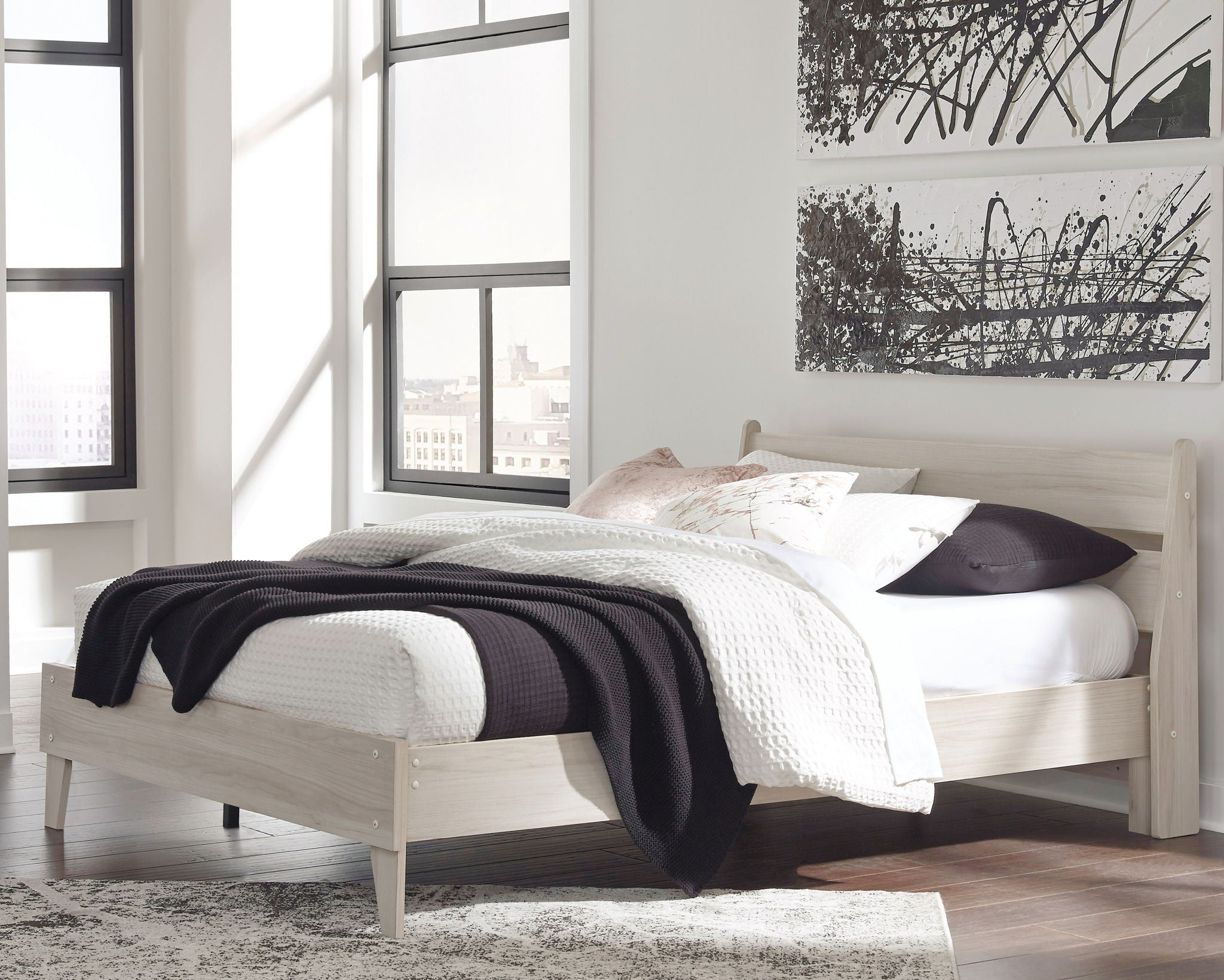 Bedroom bed frame with white bedding and dark throw blanket
