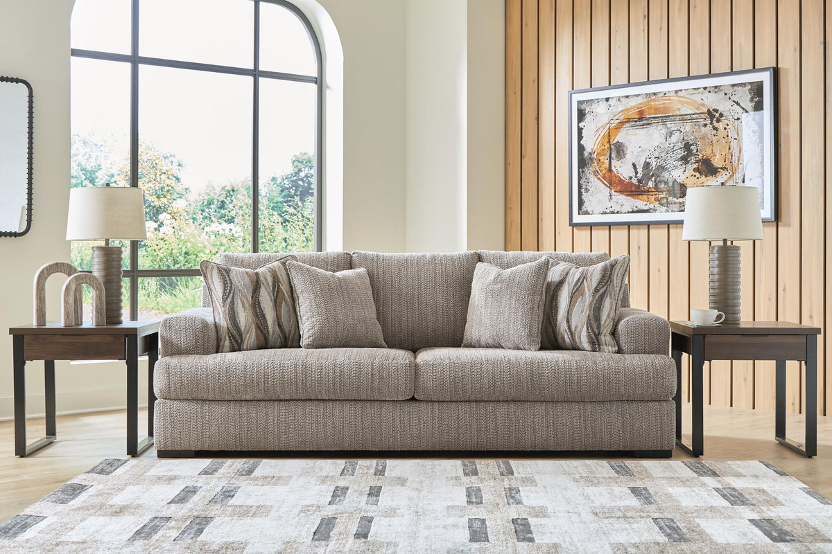 Gray fabric sofa with multiple throw pillows and dark base legs