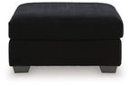 Black oversized ottoman with ribbed fabric, rounded padded top, dark legs.
