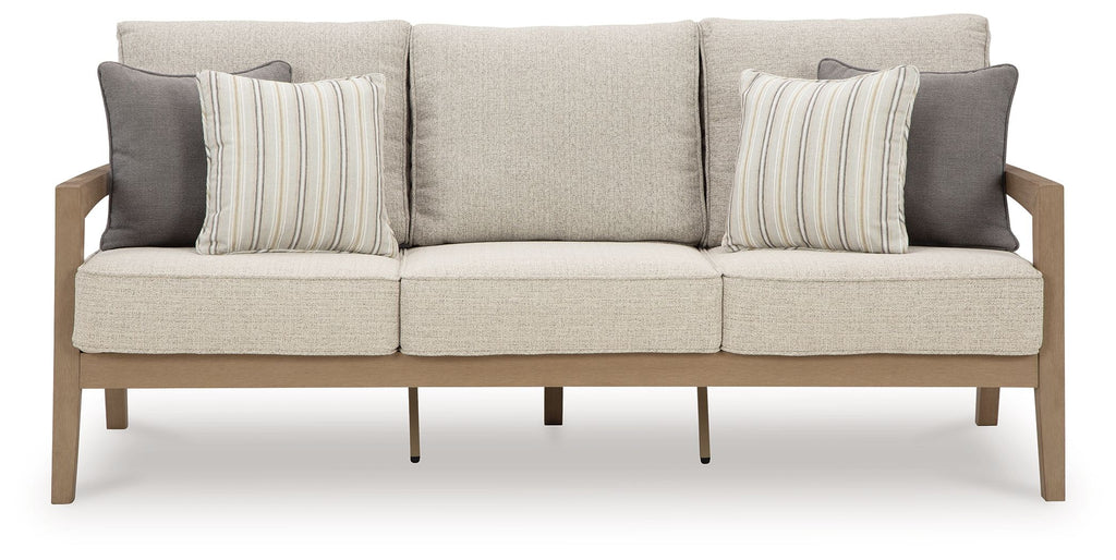 Beige fabric sofa with three back cushions, striped throw pillows, and wooden legs