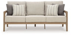Beige fabric sofa with three back cushions, striped throw pillows, and wooden legs