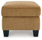 Light brown ottoman with cushioned top and side panels, dark block legs