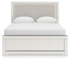 White upholstered panel bed with channel-tufted headboard, two white pillows, and paneled base