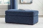 Blue upholstered ottoman with thick cushioned top and dark legs