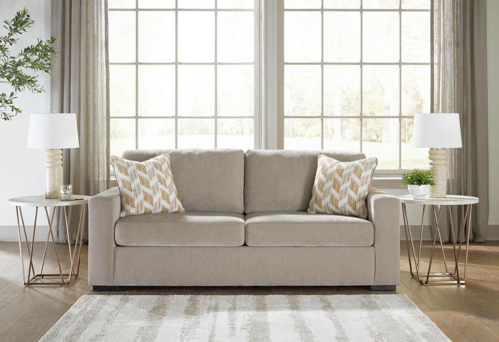 Gray upholstered sofa with two patterned pillows and two seat cushions in a room