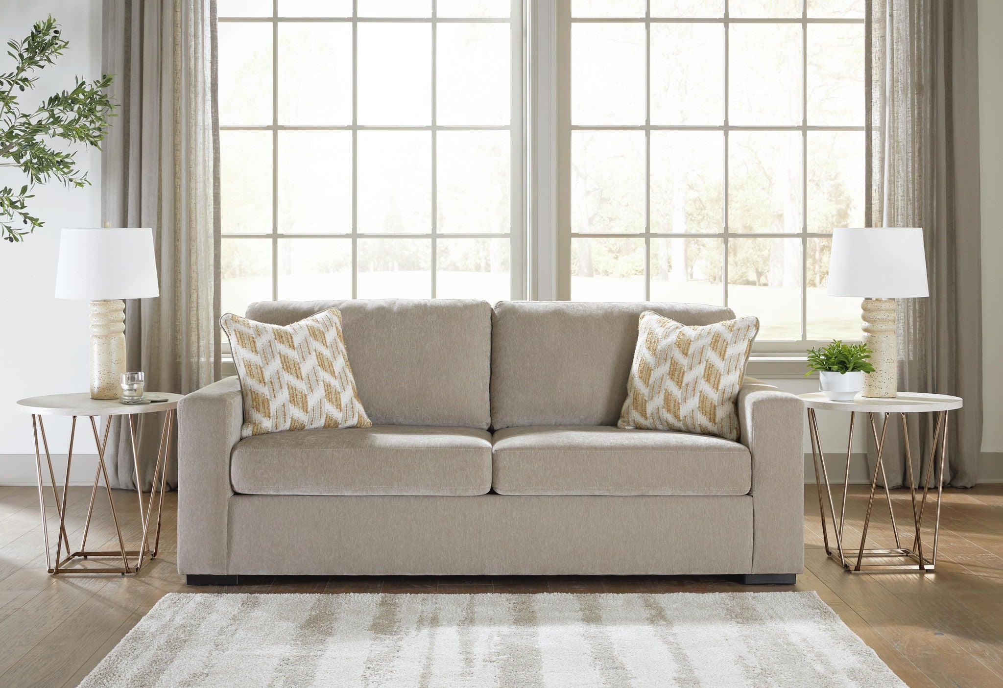 Gray upholstered sofa with two patterned pillows and two seat cushions in a room