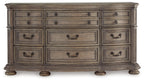 Light brown wood dresser front with rows of drawers and black handle pulls