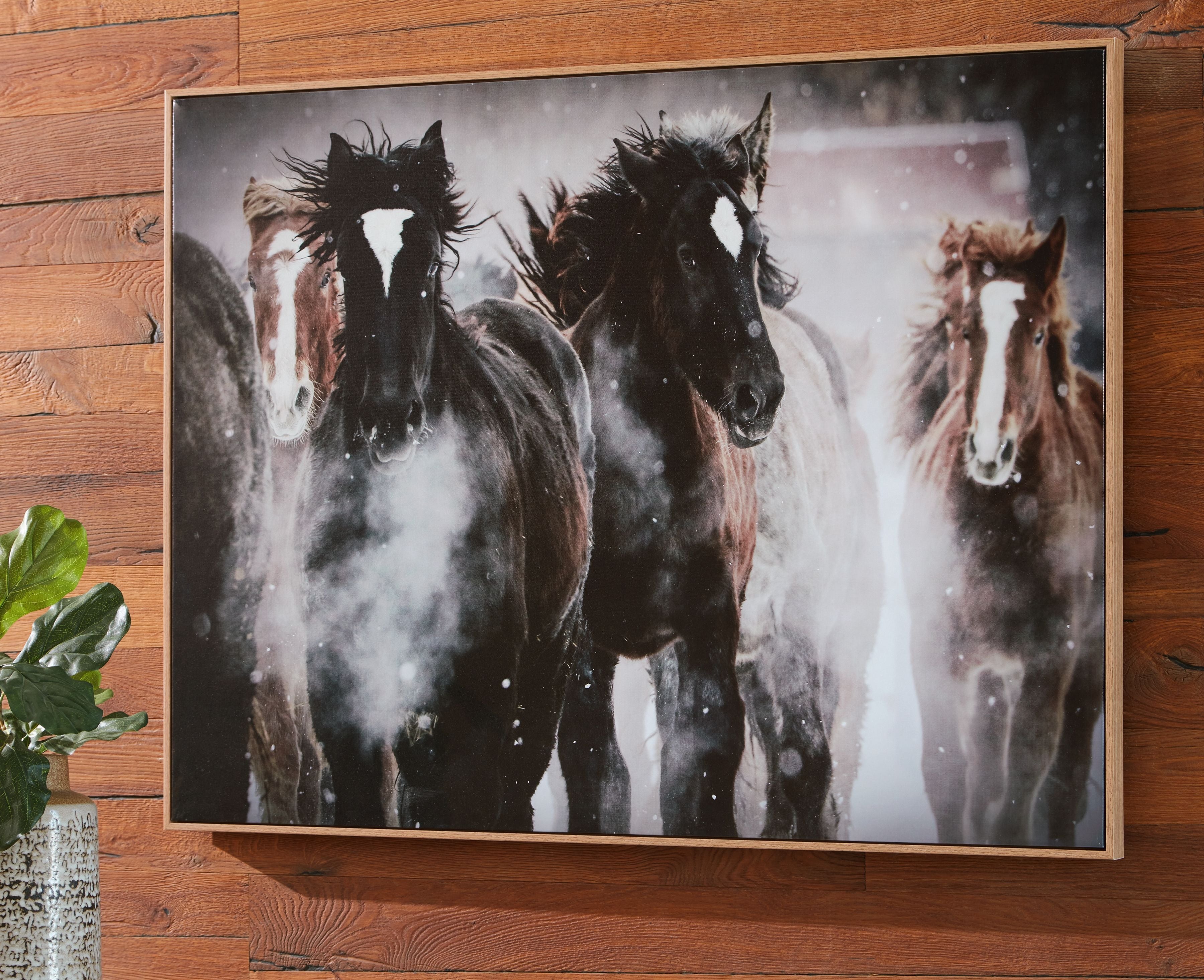 Framed wall art showing multiple horses in dark, white, and brown tones