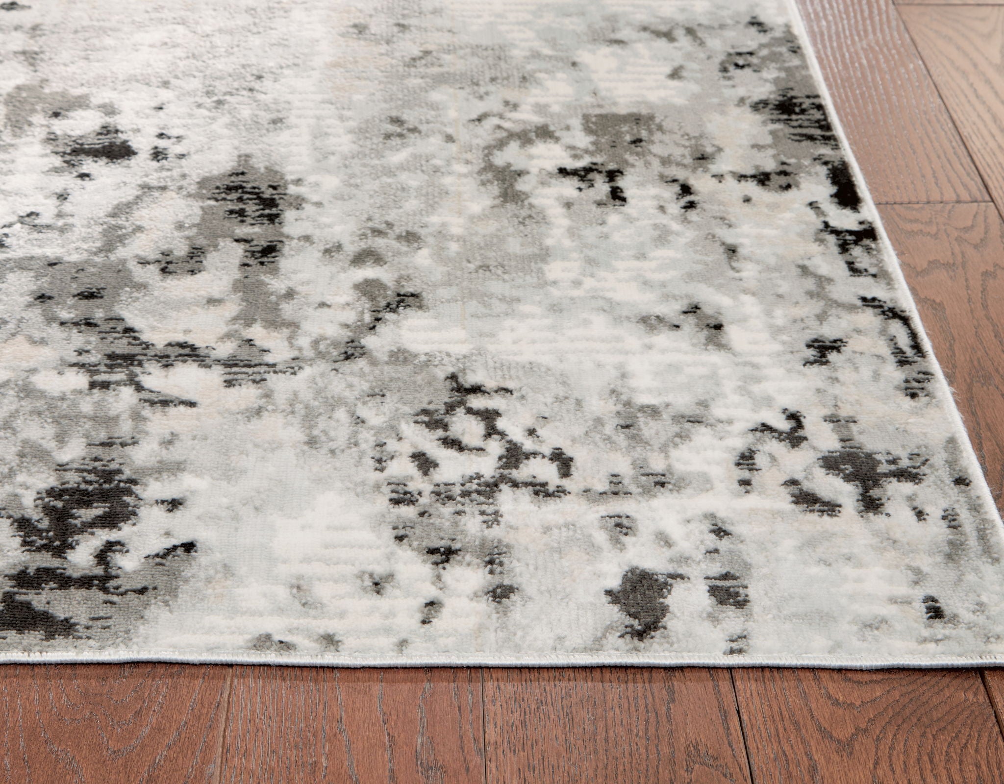 Abstract area rug close-up, light-gray base with dark speckled distressed pattern