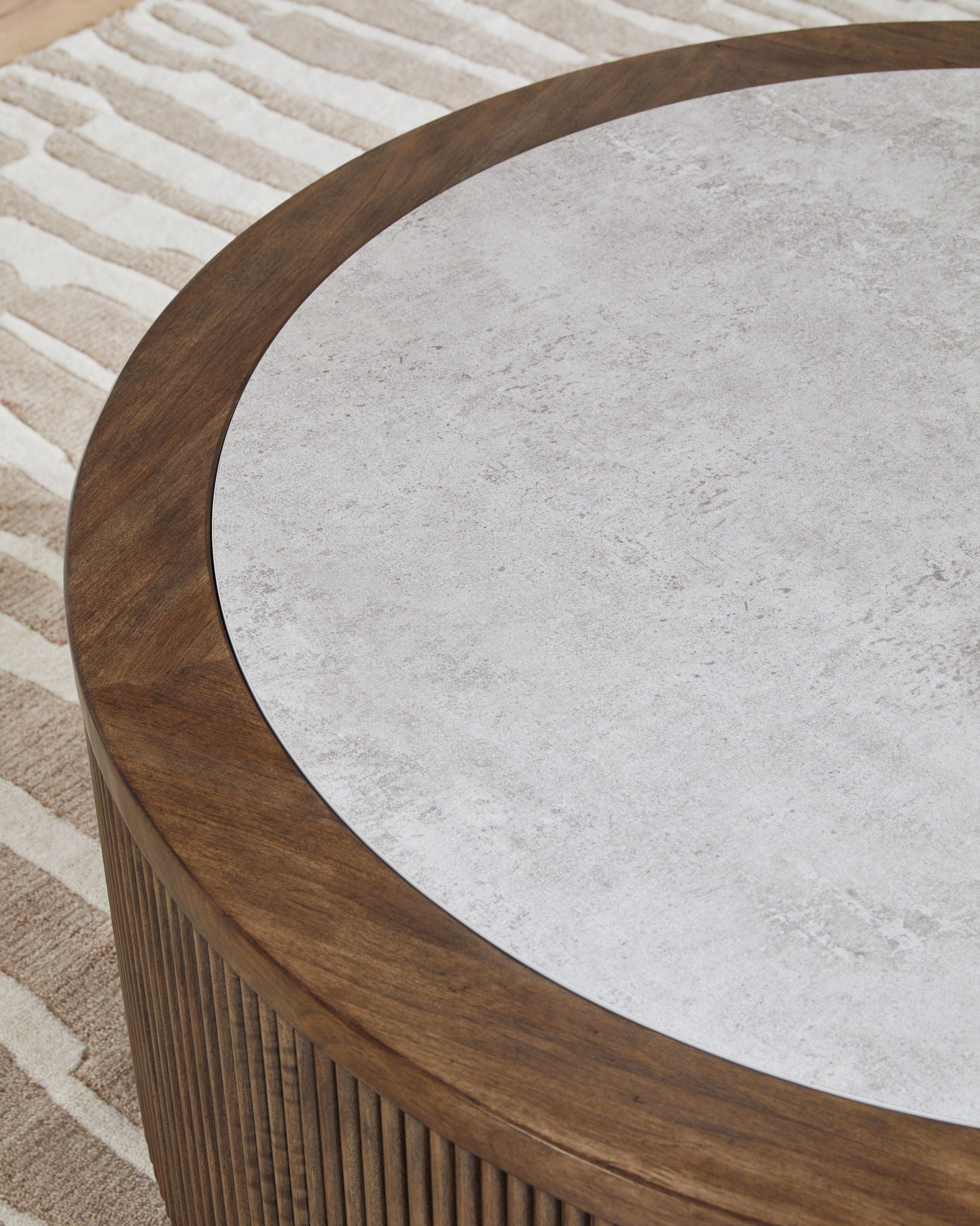 Close-up of gray round tabletop with dark wood curved edge over slatted base.