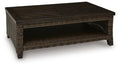 Dark brown rectangular table with woven wicker sides and open lower shelf