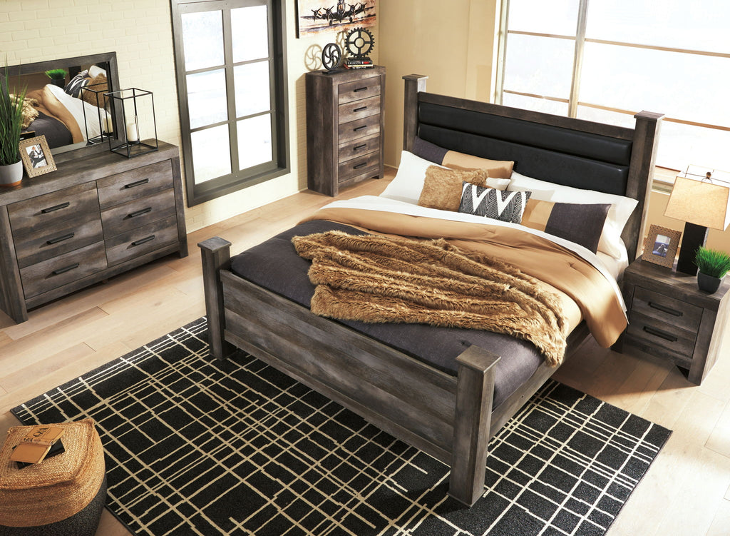 Gray poster bed with upholstered headboard, footboard, and layered bedding with pillows