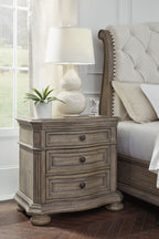 Light brown three-drawer nightstand with decorative carved base and turned legs