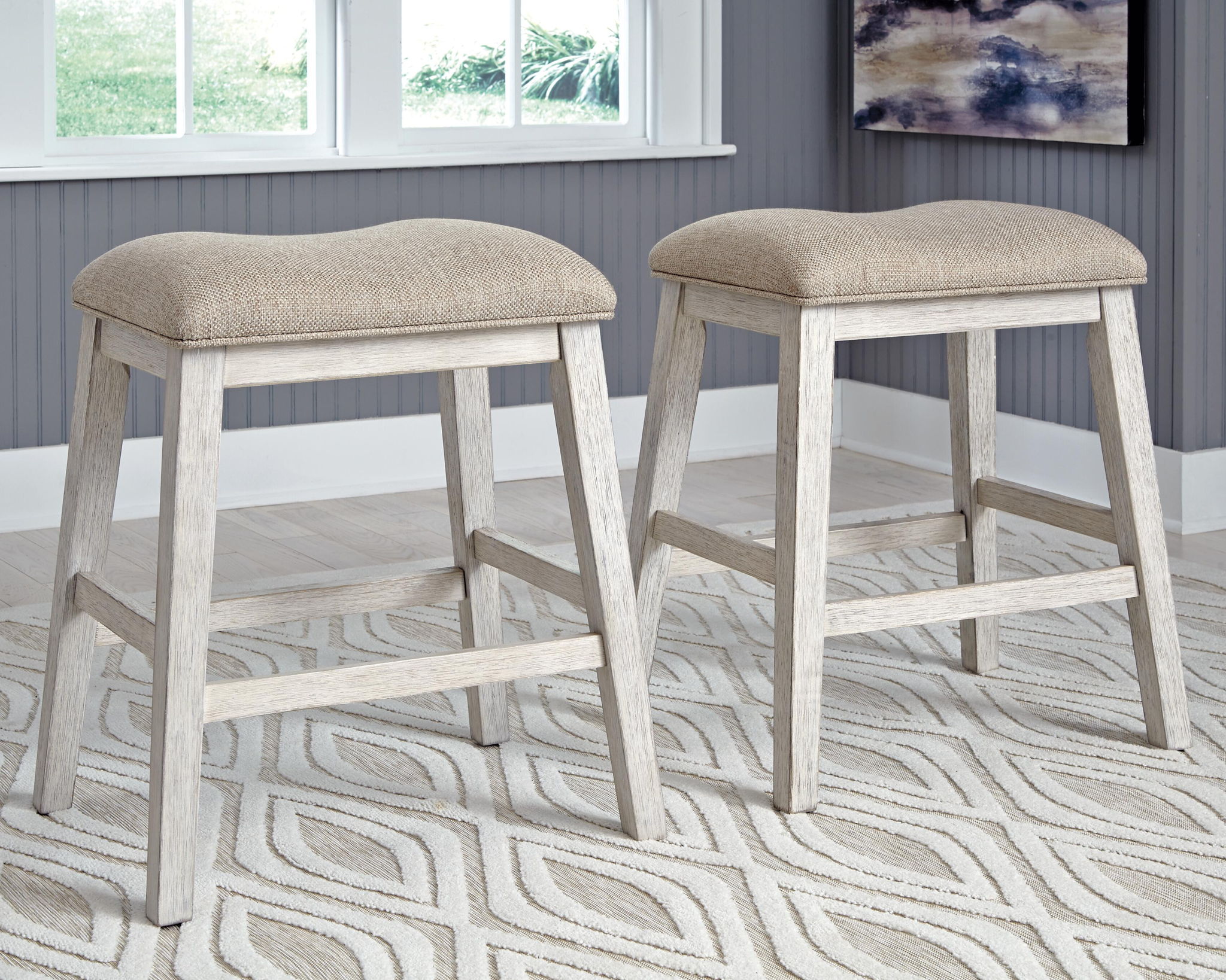 Pair of beige upholstered vanity stools with curved seat tops and matching wood footrest