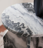 Accent table close-up: round marble-look top edge with black, gray, and white veining