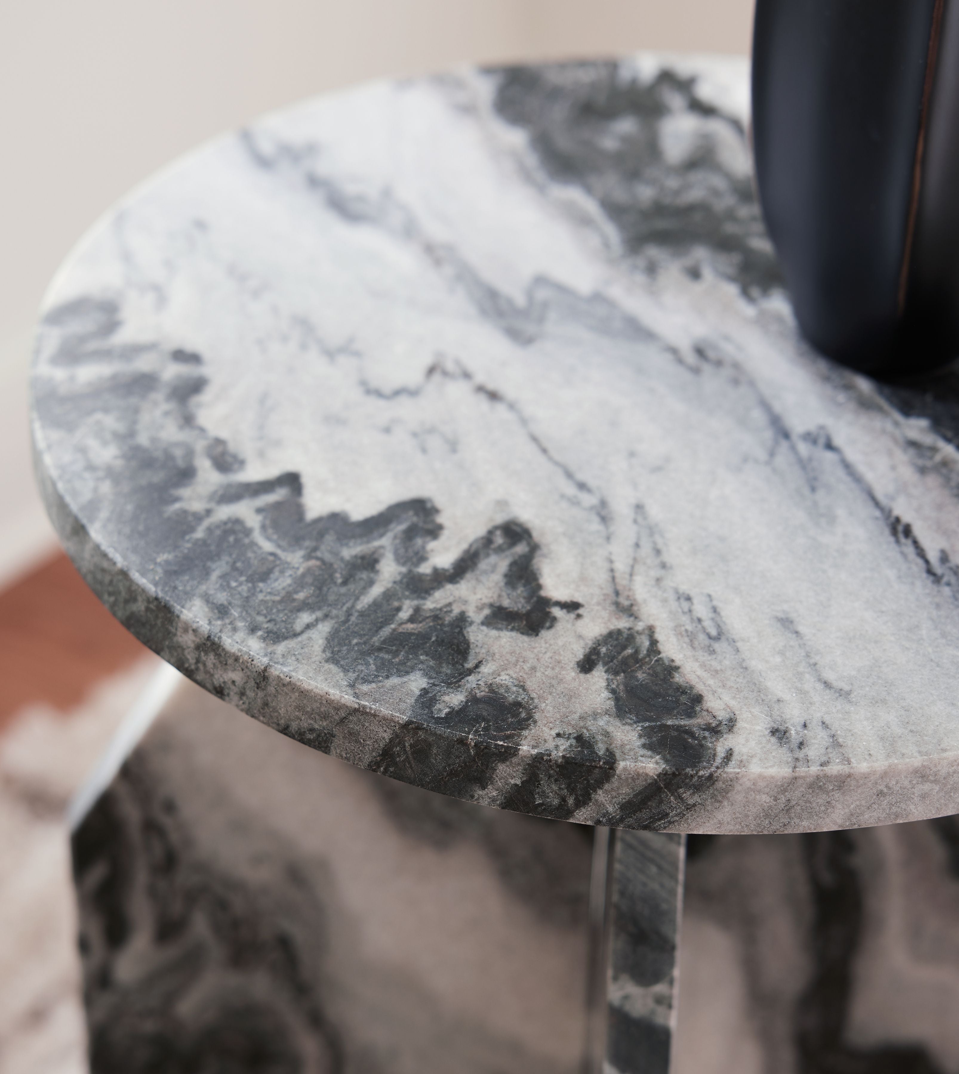 Accent table close-up: round marble-look top edge with black, gray, and white veining