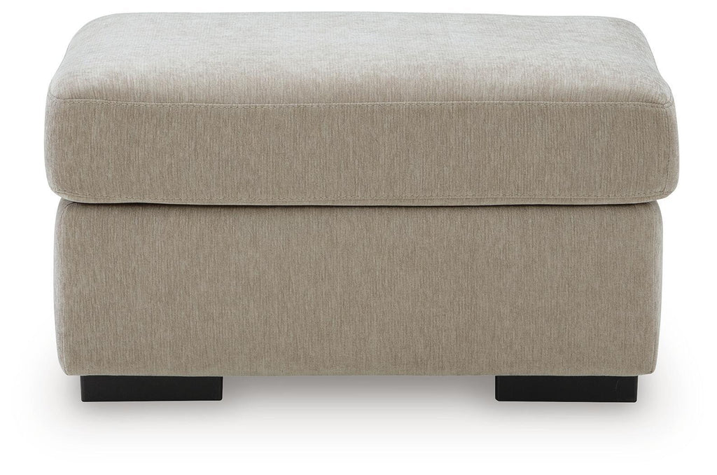 Light beige upholstered ottoman with thick padded seat and black legs
