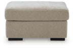 Light beige upholstered ottoman with thick padded seat and black legs