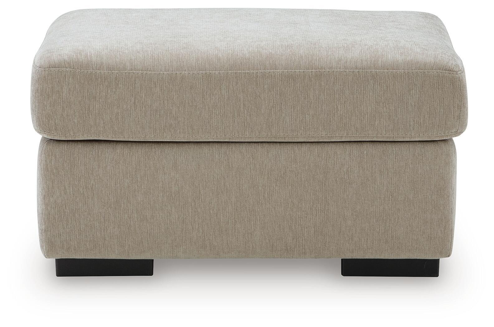 Light beige upholstered ottoman with thick padded seat and black legs