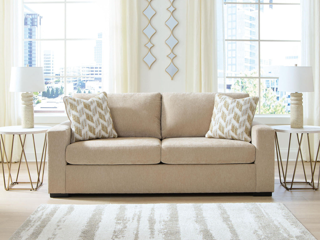 Light brown sofa with two seat cushions and two patterned throw pillows