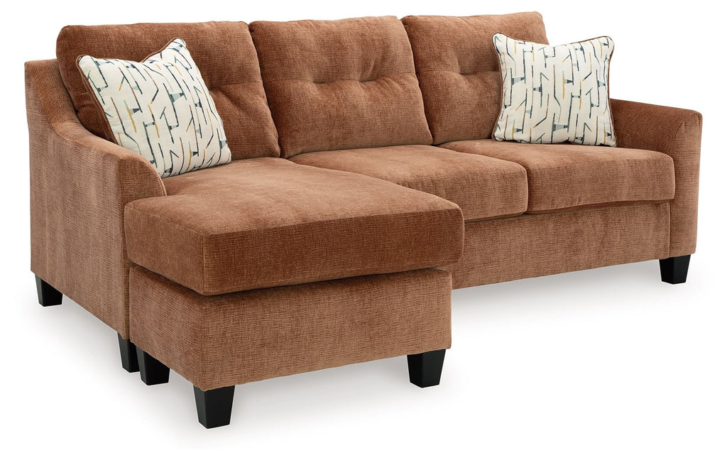 Brown sofa with chaise and ottoman, with patterned accent pillows and black legs