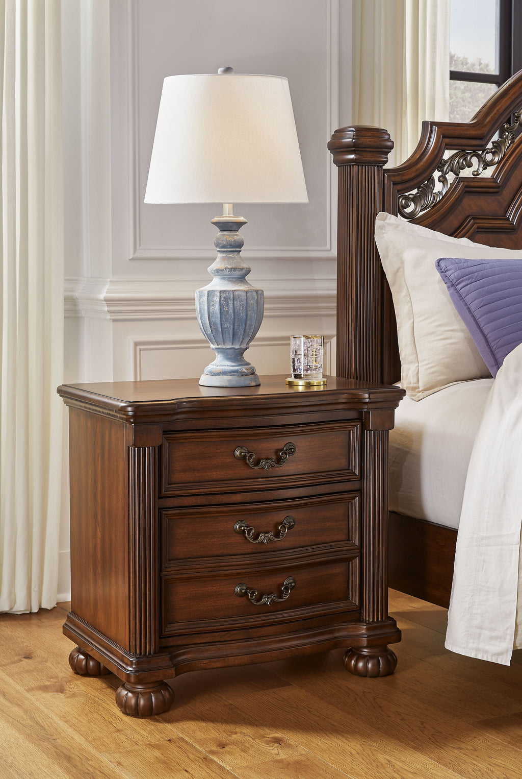 Lavinton three-drawer night stand in brown wood with brass-tone drawer pulls and turned feet