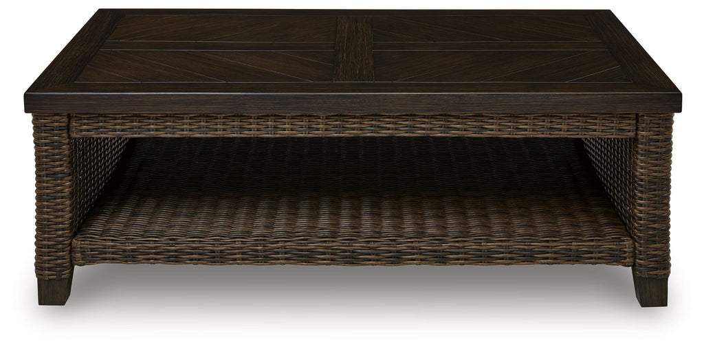 Rectangular patio coffee table with dark brown tabletop and woven base with open shelf