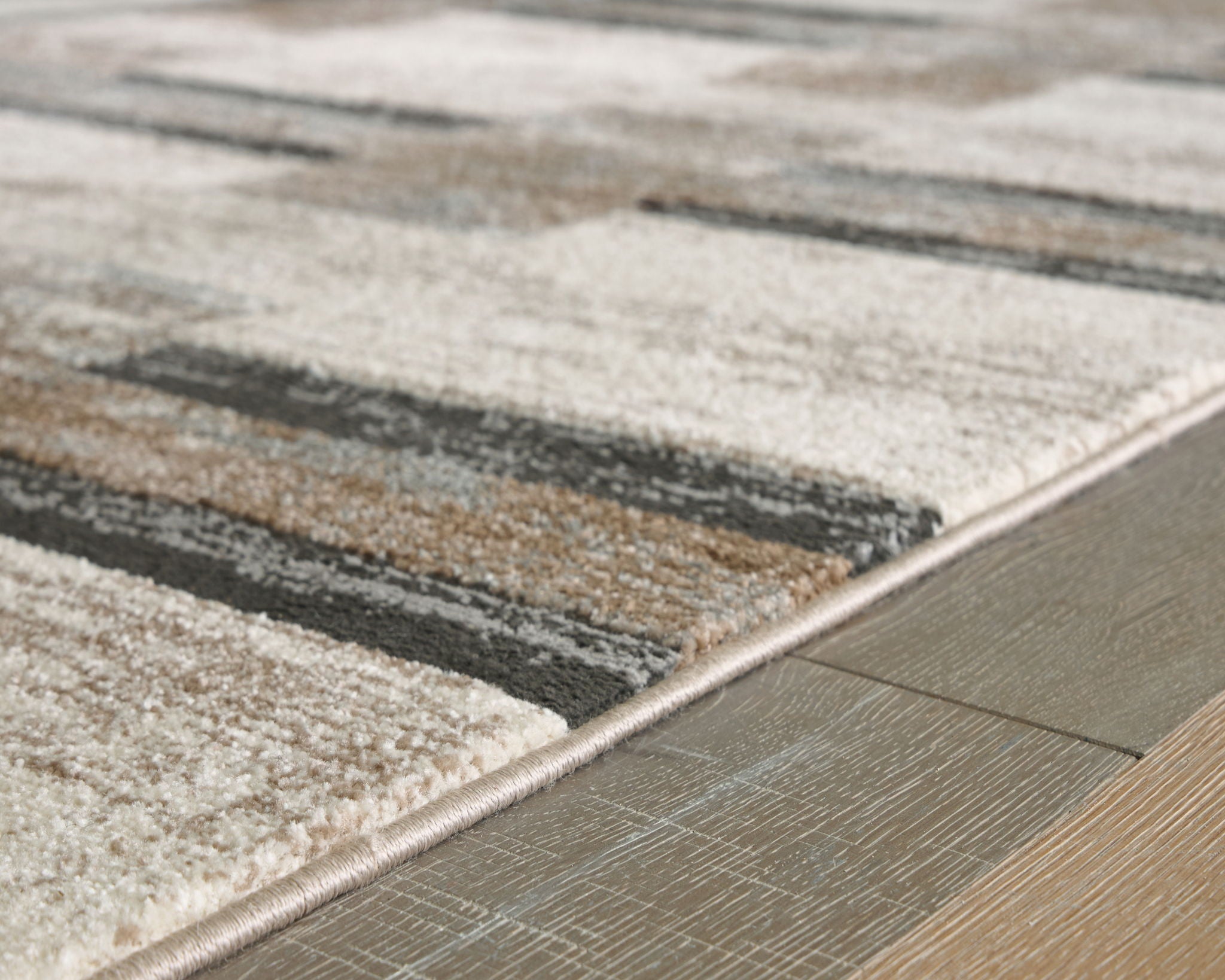 Beige abstract block area rug corner with dark gray stripes and bound edge