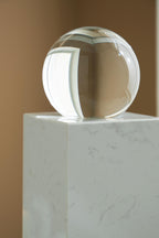 White glass sphere on white marble pedestal, close top angle