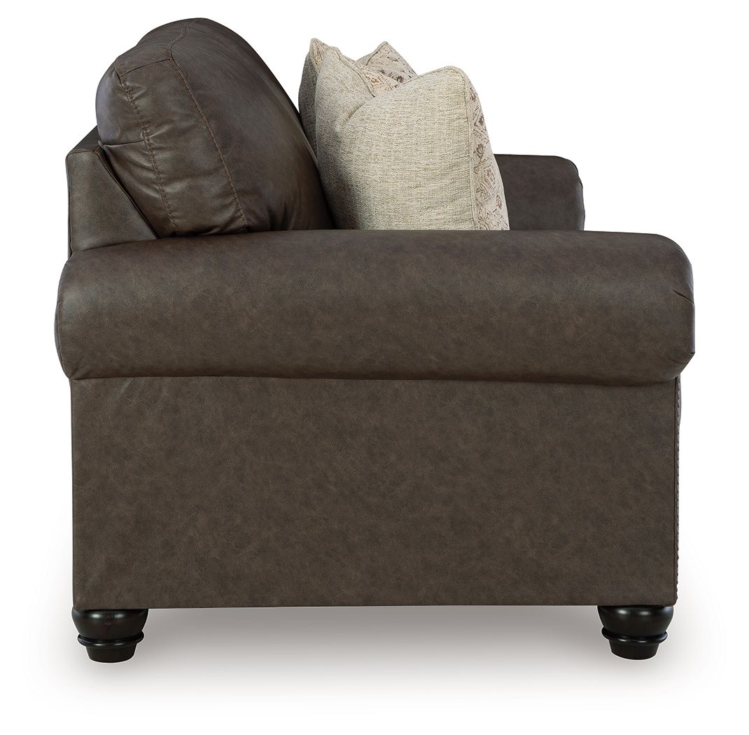 Umber loveseat with tufted back, track arms, and two patterned throw pillows