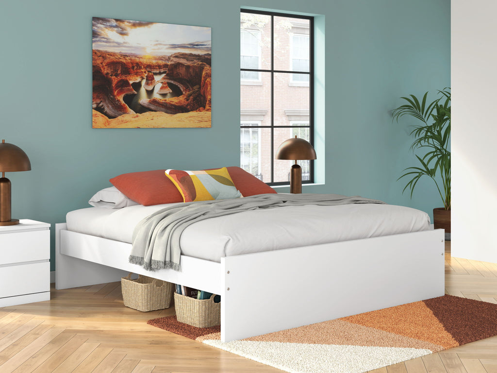 White platform bed with drawers and neatly styled bedding, side view