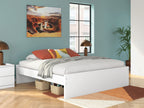 White platform bed with drawers and neatly styled bedding, side view