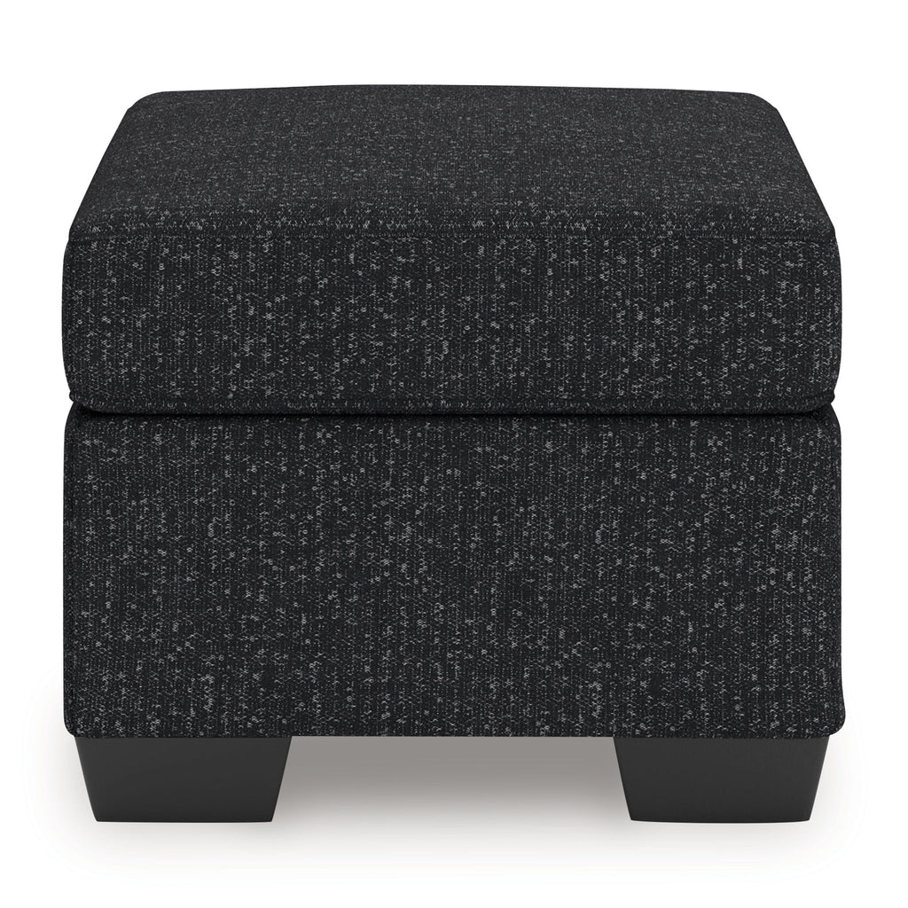 Upholstered ottoman with dark textured fabric, padded top, and short legs