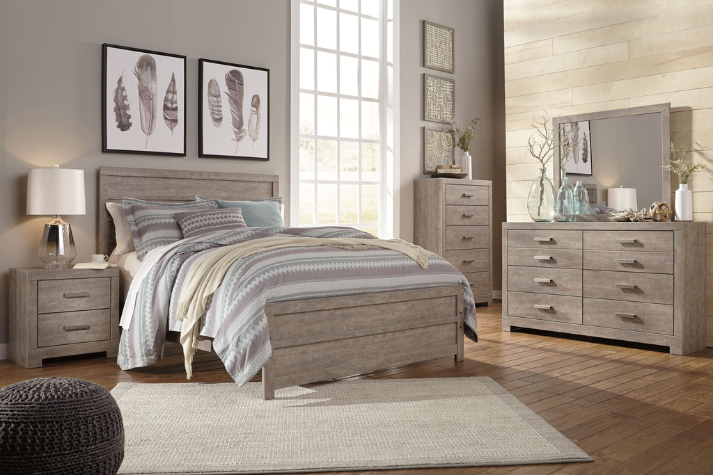 Gray panel bed with upholstered headboard and storage drawers, styled with bedding set