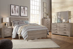 Gray panel bed with upholstered headboard and storage drawers, styled with bedding set