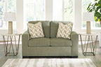 Olive green upholstered loveseat with two patterned accent pillows and square arms